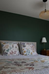 a bed with two pillows and a green wall at Au Jardin de Mireille in Leffrinkhoucke