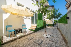 a patio with two chairs and an umbrella and a tree at NEV Fethiye in Fethiye