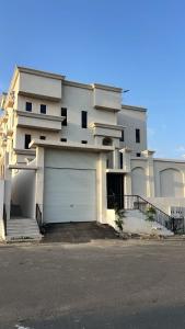 a white house with a garage in front of it at شقق واحة المحمدية in Baljurashi