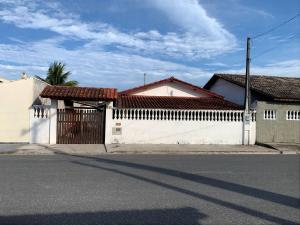 a white house with a gate and a fence at Casa temporada Ilha Comprida 350m da praia in Ilha Comprida