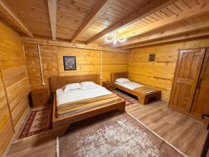 a bedroom with two beds in a wooden room at Valbone Two E in Valbonë