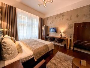 a bedroom with a bed and a desk and a television at Alfons Boutique Hotel in Prague