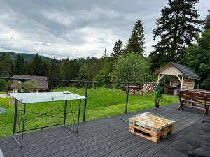 eine Tischtennisplatte auf einer Holzterrasse mit einem Park in der Unterkunft LUCE Chata in Nieledwia