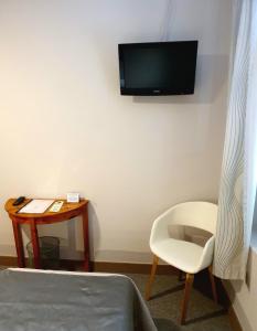 a room with a bed and a chair and a tv on the wall at Hôtel Restaurant le Provence in Brignoles