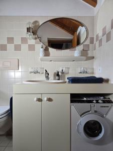 a white bathroom with a sink and a mirror at Rustico Marietta by HolAp SA in Brissago +28 photos