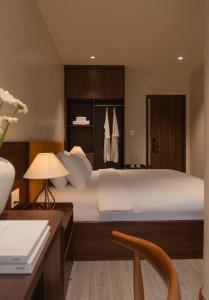 a bedroom with a large white bed and a desk at Velora Hotel DaLat in Xuan An