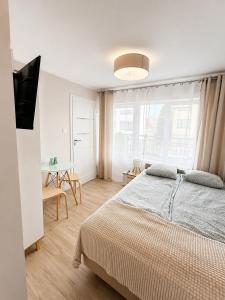 a bedroom with a bed and a table and a window at Oaza Leba - Idealny dla rodzin z dziecmi in Łeba