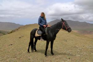 a woman riding a black horse on a hill at Hidden Valley Guesthouse in Toguz-Bulak