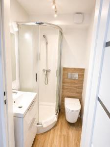 a white bathroom with a shower and a toilet at Oaza Leba - Idealny dla rodzin z dziecmi in Łeba +49 photos