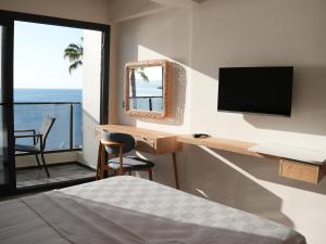 a bedroom with a bed and a desk with a television at Ciftlique Otel Cesme in Çeşme