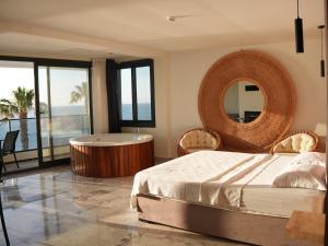 a bedroom with a tub and a bed and a mirror at Ciftlique Otel Cesme in Çeşme