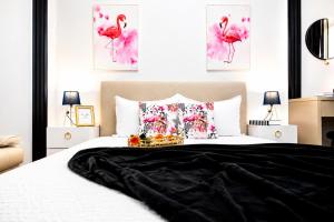 a bedroom with a large bed with pink flamingos paintings at OCCO by the Jacuzzi in Popeşti-Leordeni