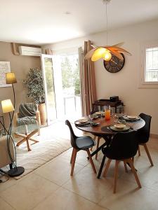 a dining room with a table with chairs and a clock at Le murmure des pins in Villemoustaussou +40 photos