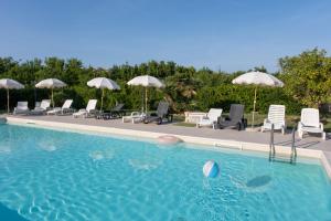 a large swimming pool with chairs and umbrellas at Al Palmento Country Hotel in Syracuse