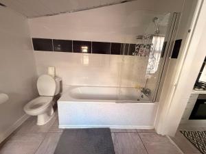a white bathroom with a tub and a toilet at Cosy Heavens in Quinton