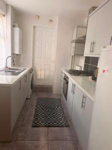 a kitchen with white cabinets and a black and white rug at Cosy Heavens in Quinton