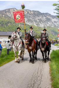 three men on horses holding a flag on a road at Hotel Bräuwirt in Kirchberg in Tirol