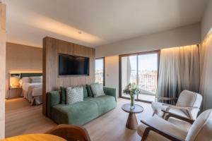a hotel room with a green couch and a bed at Turia Badajoz in Badajoz