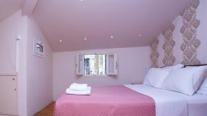 a bedroom with a pink and white bed with a window at Guilford Loft in Corfu