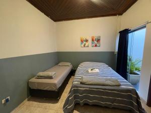 two beds in a room with a window at ACONCHEGO 6 - Self Check-in in Presidente Prudente