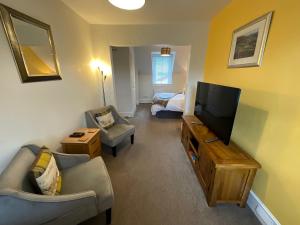 a living room with a couch and a tv and a bed at Craigbank Guest House in Crianlarich