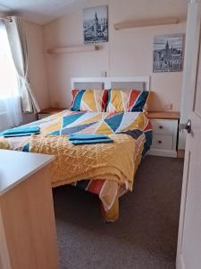 a bedroom with a bed with colorful sheets and a desk at Stay 6 - Pool - Parking - BeachSide - Pet Friendly in Trimingham +23 photos