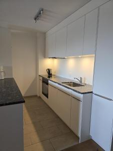 a kitchen with white cabinets and a sink at Bella Val (206 Se) in Lenzerheide +4 photos