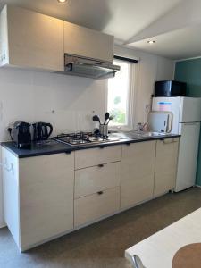 a kitchen with a stove and a sink and a refrigerator at Mobilhome camping St jacques in Sarzeau