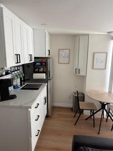 a kitchen with white cabinets and a table and a refrigerator at Newly Renovated 1BR Suite, Patio BBQ, Fire Pit in Simi Valley