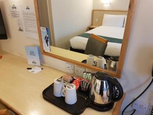 a hotel room with a desk with a bed and a mirror at Days Inn Sutton Scotney North in Sutton Scotney