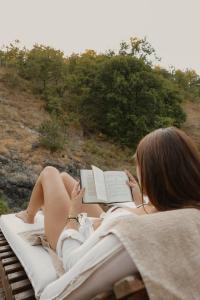 a woman laying on a bed reading a book at Zicka plaza in Kraljevo