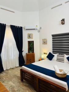 a bedroom with a large bed with blue pillows at Villa Lemon in Varkala
