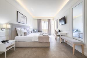 a white bedroom with a large bed and a desk at Hotel Eden in Budva +42 photos