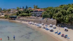 a beach with a bunch of chairs and umbrellas at Ancora Beach House by "elite" in Tsilivi