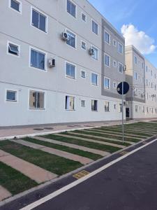 a large white building with grass in front of it at Apartamento Espaço e Conforto Cerejeiras in Várzea Grande