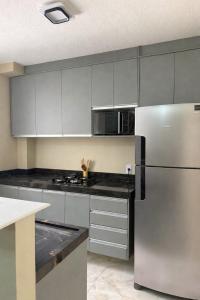 a kitchen with white cabinets and a stainless steel refrigerator at Apartamento Espaço e Conforto Cerejeiras in Várzea Grande