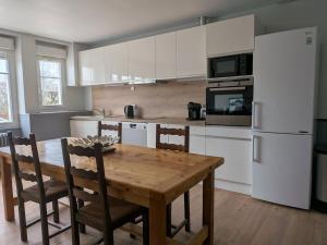 a kitchen with a wooden table and a white refrigerator at Gîte LM in Bourbonne-les-Bains