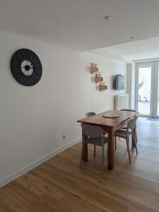 a dining room with a table and a clock on the wall at Gîte LM in Bourbonne-les-Bains +3 photos