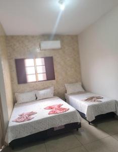 a room with two beds with pink flowers on them at LD Hotel in Três Lagoas