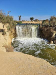 a waterfall on the side of a river in the desert at Safarova Tours in Fayoum