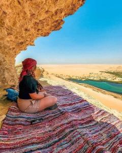 a woman sitting on a rug on a cliff at Safarova Tours in Fayoum