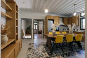 a kitchen and dining room with a wooden table and yellow chairs at Mesta Grand Residence in Chios