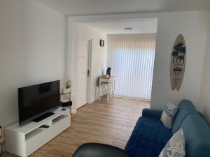 a living room with a blue couch and a television at La Cabane Marine in Sangatte
