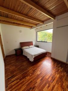 a bedroom with a bed and a large window at Refugio de Guacamayas in Mérida