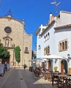 a building with tables and umbrellas in a courtyard at St Jordi Hagdigadar Tossa in Tossa de Mar