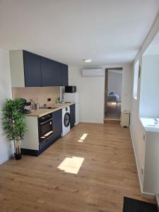 a kitchen with blue cabinets and a wooden floor at T2 proche gare & centre ville climatisé in Castres