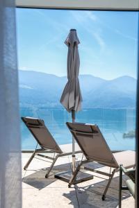 two chairs and an umbrella sitting on a balcony at Exclusive Boutique Hotel Elisabetta in Ronco sopra Ascona