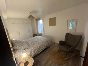 a bedroom with a bed and a chair and a table at Le Gîte Chez Mémé in Lavelanet
