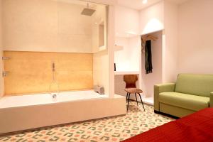 un bagno con vasca, sedia e divano di Limen Matera Guesthouse a Matera