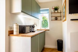 a small kitchen with green cabinets and a microwave at The Hide at St Andrews in Fife